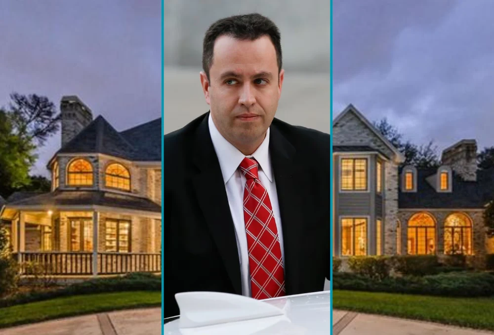 Exterior view of Jared Fogle's house, a large brick home with a neatly maintained lawn, trees, and a driveway, set against a clear blue sky.