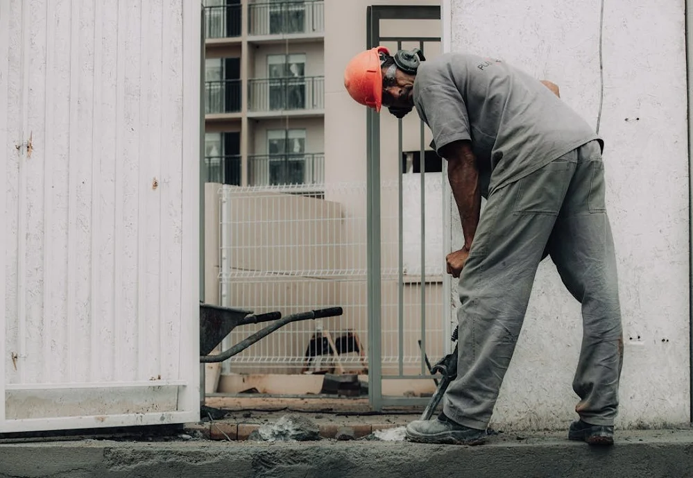 How Concrete Core Drilling Differs Between Homes and Businesses - Building & Construction - Homedecortoday A man wearing an orange helmet using portable concrete drilling equipment for precise holes in a construction project.