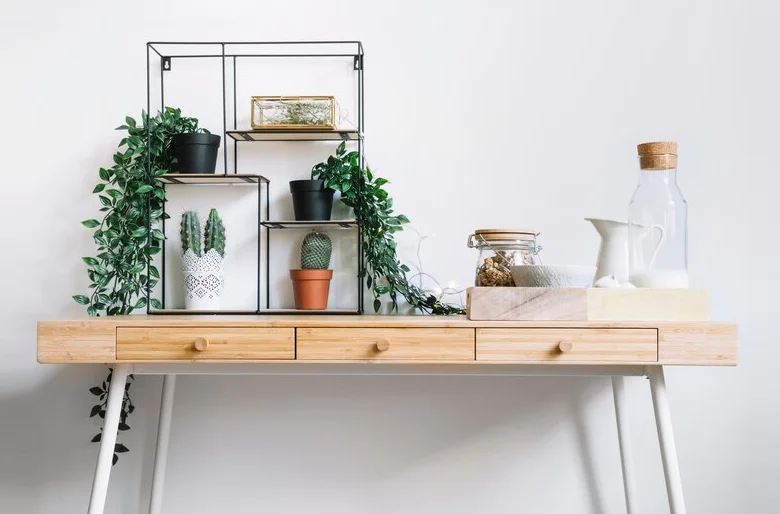 Wooden desk with black metal shelves holding potted plants and storage jars, showcasing creative DIY shelving for organized spaces.