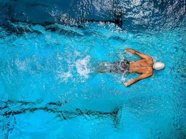 Is a Pool a Good Investment? Smart Reasons to Add Swimming Pools to Your Home - DIY Projects - Homedecortoday Man swimming in a pool showing benefits of swimming pool investment for fitness and relaxation.