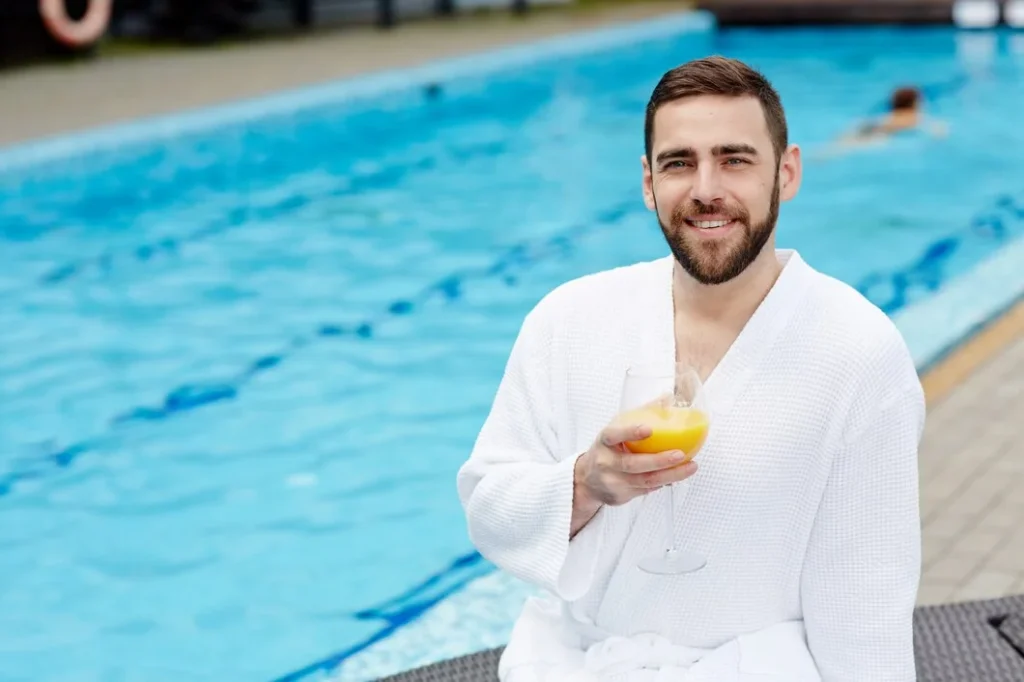 Man relaxing poolside showing lifestyle benefits from a swimming pool investment.