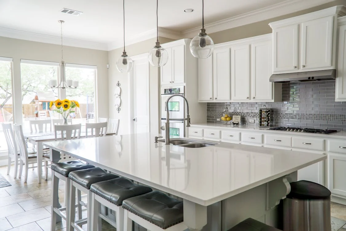 Transformed modern kitchen with white cabinets, island, and pendant lighting